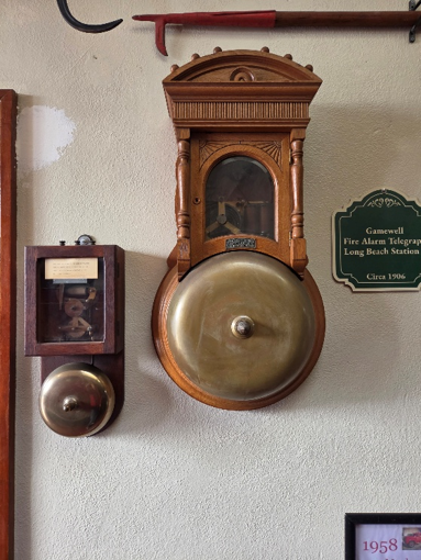 Two Gamewell fire alarm bells — a large bell rescued from Fire Station 1 after the 1933 Long Beach earthquake, and a smaller bell used in an officer's home